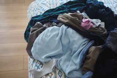 Evde çamaşırları yıkadıktan sonra giysiler bir yatağa saçılmış..