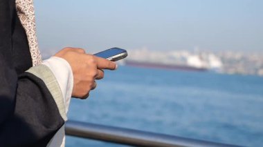 Birisi rıhtımda dururken akıllı telefonunu kontrol ediyor..