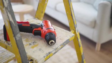 Kablosuz matkap, rahat ve modern bir yaşam alanındaki bir merdivenin üzerinde duruyor..