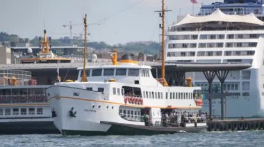 Limandaki hareketli hareketliliğin ortasında bir feribot iskeleye yaklaşıyor..