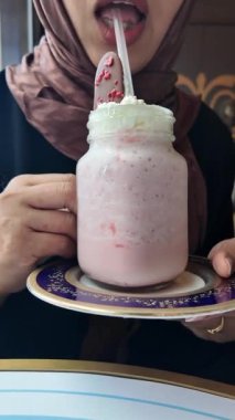 Bir insan üzerinde krem şanti ve kaşık olan pembe bir milkshake 'i sever..