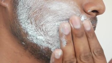 Yüz kremi erkek yüzüne sürülüyor. ,