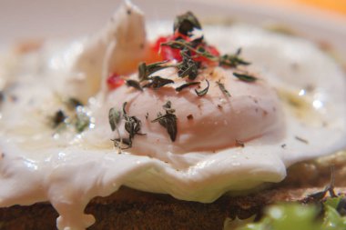 Kavrulmuş bir yumurta, otlar ve baharatlarla süslenmiş kızarmış ekmeğin üzerinde oturur..