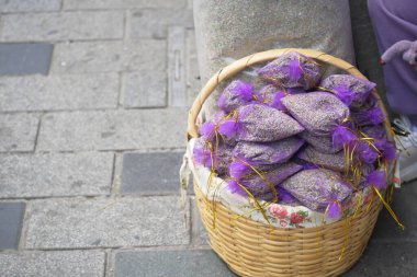 Kentsel kaldırımda sergilenen lavanta keseleriyle dolu dokuma sepet..