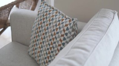 Rahat bir oturma odasında yumuşak bir kanepeye yerleştirilmiş desenli bir yastık var..
