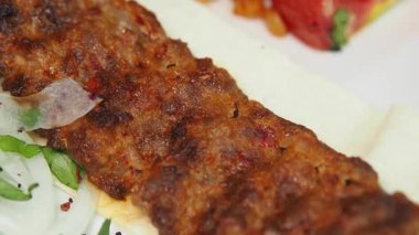 Baharatlı Adana ızgara et ve yanında canlı salata ve malzemeler..