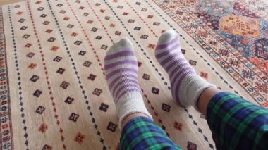 Rahat bir an, parlak desenli bir halıda rahat çizgili çoraplarla..