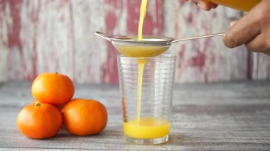 Portakal sıkmak ve meyve suyunu yakınlarda taze meyvelerle bir bardağa doldurmak..