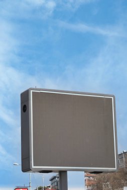 Güneşli bir gökyüzünün altında boş bir dijital reklam panosu duruyor..