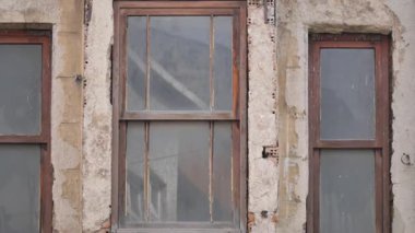 Yaşlanan bir yapıda yıpranmış pencerelerin ayrıntılı görünümü.