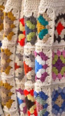 Canlı tığ işi yamalar rahat ve sanatsal bir kumaş görüntüsü oluşturur.