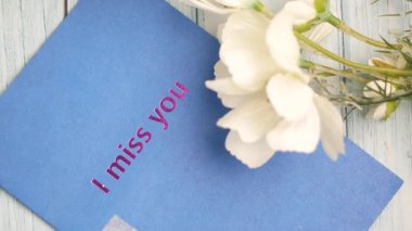 Yürekten bir kart, yanında beyaz çiçeklerle seni özlediğimi gösteriyor..