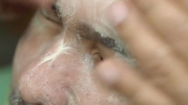 Bir adam cilt temizleme tekniklerine odaklanarak, ürününü yüzüne uygular..