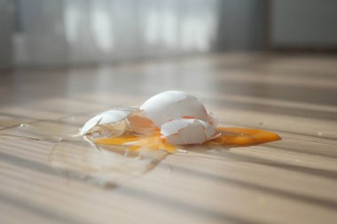Kırık yumurtalar ve sarı sarısı gün ışığında ahşap bir yüzeyi kaplıyor..