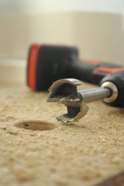 Testereli bir matkap ahşap talaşlarının yanına yerleştirilmiş..