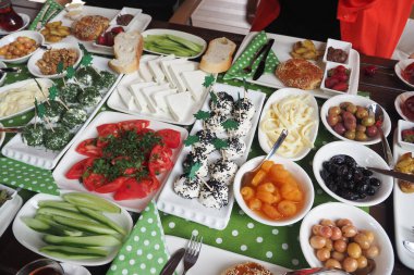 Çeşitli sebzeler, peynirler ve ekmekle dolu canlı bir kahvaltı masası..