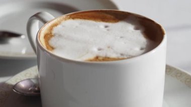 Rahatlatıcı bir atmosferde köpüklü sütlü sıcak bir kahvenin tadını çıkar..