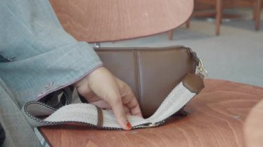 Kafede kahverengi deri bir çanta takan bir kadın..