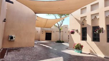 Çiçekler ve gölgelerle süslenmiş büyüleyici bir avluda geziniyor..