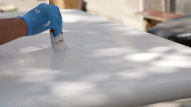 Güneş ışığının tadını çıkarırken bir el yüzeyi beyaza boyar..