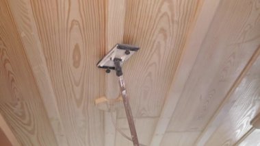 İşçiler parlak bir odadaki ahşap tavana son rötuşları yapıyorlar..