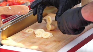 Bir satıcı, kalabalık bir pazarda müşteriler için ustalıkla dilimlenmiş muz hazırlar..