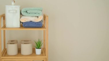 Ahşap bir rafta düzgün düzenlenmiş havlu ve aksesuarlar temiz bir görünüm oluşturur..