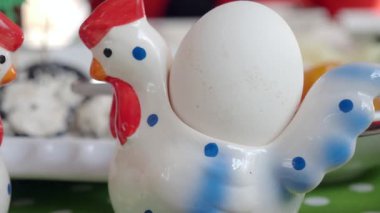 Neşeli bir seramik tavuk canlı bir yemek alanında beyaz bir yumurta sergiler..