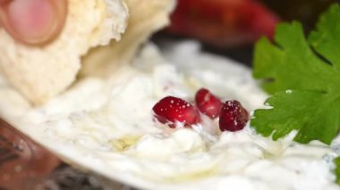 Nar ve otlarla kaplı lezzetli bir yoğurt tabağı servis edilir..