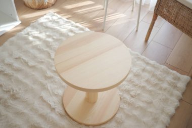 Samimi bir odada, desenli bir halıda basit bir ahşap masa bulunur..