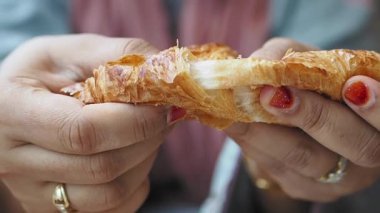 Bir insan yeni pişmiş kruvasan yemekten zevk alır ve onu parçalara ayırır..