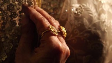 Zarif ellerin yakın çekimi göz kamaştırıcı altın yüzükler sergiliyor..