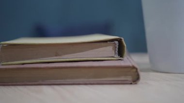 İki kitap tahtadan bir masanın üzerinde, sakince duran bir bardağın yanında..