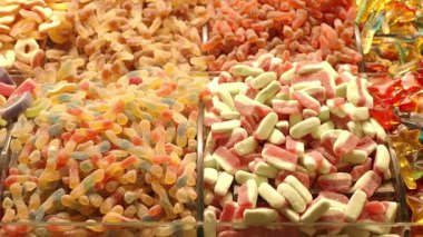 Hareketli pazar ortamında sepetleri dolduran çeşitli şekerler..