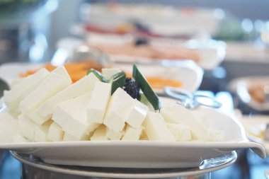 Çeşitli yemekler arasında sergilenen bir tabak beyaz peynir..