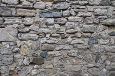 Yıpranmış taşlar, tarihi ve becerileri vurgulayan dokulu bir duvar oluşturur..