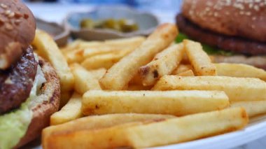 İki lezzetli hamburger tabakta altın kızartmaların yanında oturup yemeye hazır..