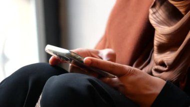 Bir insan rahatça otururken akıllı telefonuna odaklanır..