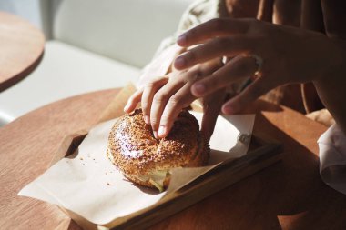 Eller, kafedeki ahşap bir tabakta duran sıcak bir pastaya nazikçe dokunur..
