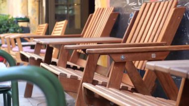 Tahta sandalyeler, sıcak güneş ışığı altında bir kafe önünde davetkar bir şekilde dizilmiş..