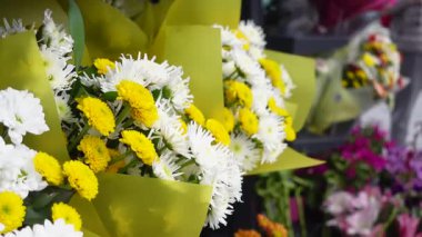 Hareketli bir pazarda canlı sarı ve beyaz çiçek buketleri.