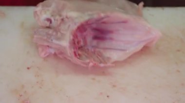 Bir aşçı bir tarif için çiğ tavuğu ustalıkla küçük parçalara ayırır..