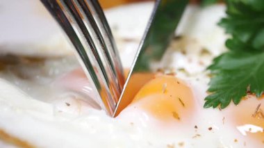 Canlı yumurta sarısını dilimleyen çatal ve bıçağın yakın çekimi..