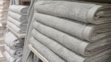 Rahat keten mağazasında raflarda düzgünce sergilenen yumuşak gri havlular sergileniyor.