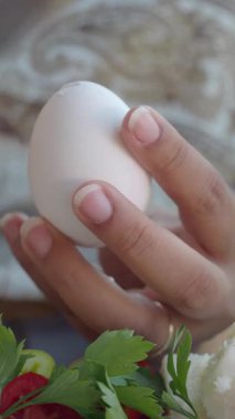 Bir eli nazikçe tut. Beyaz bir yumurtayı tut. Etrafı otlarla çevrili..