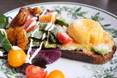 Brunch, yumurta, salata ve taze sebzeli canlı bir tost tabağı sunar..