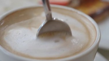 Bir kahve fincanının karıştırılmasının yakından görüntüsü köpüklü desenler yaratıyor..