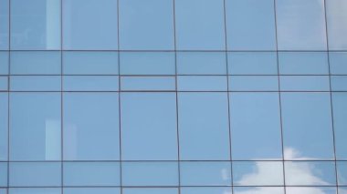 Mavi gökyüzünün altındaki modern camdan yansımalar parlıyor..