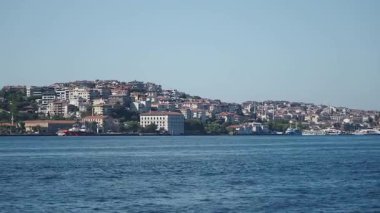 Sudan görünen tepeleri ve binaları olan sahil şehri..