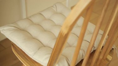 Yumuşak, şık bir yastık evdeki rahatlık için ahşap bir sandalyeye yerleştirilmiş..